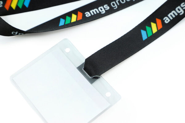 Ansicht vor dem Zusammenbau, die ein schwarzes Polyester-Lanyard mit Befestigungsschlitzen neben einem durchsichtigen Kunststoff-Ausweishalter zeigt.