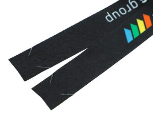 Ein langer, flacher Streifen bedruckten Polyesterbands, bereit zur Montage zu einem individuellen, hakenlosen Werbe-Lanyard.